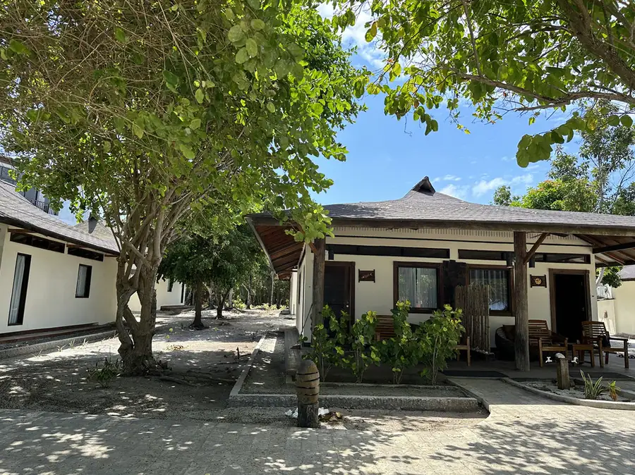 A quaint garden-facing cottage with white siding at Mussah Poteh Resort