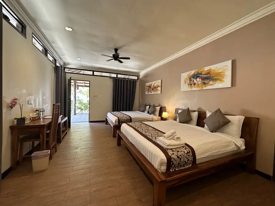 A bright bedroom featuring two beds with elegant red runners at Mussah Poteh Resort