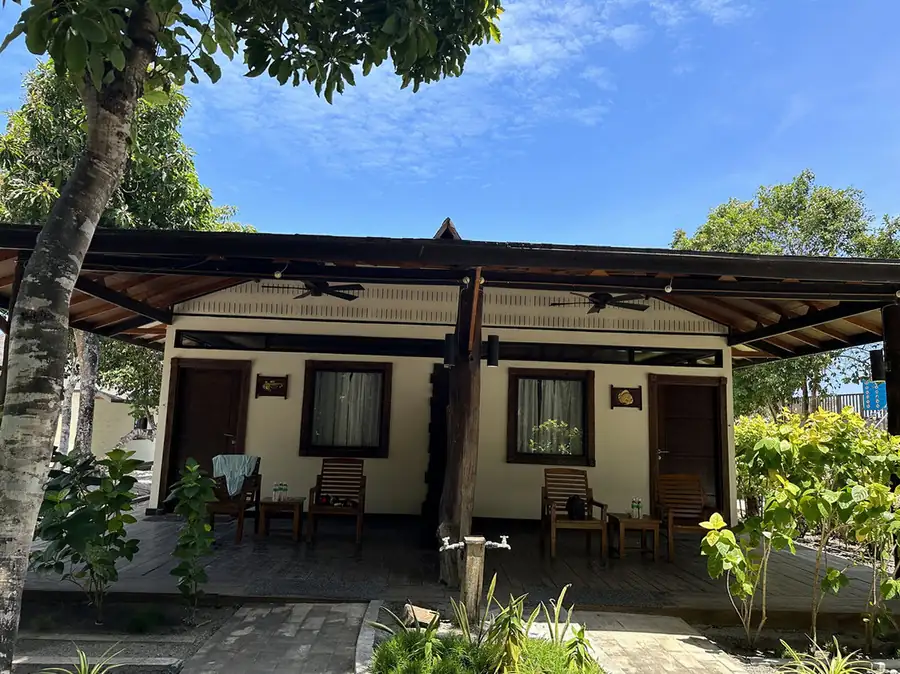 A white garden chalet featuring a blue corrugated roof at Mussah Poteh Resort