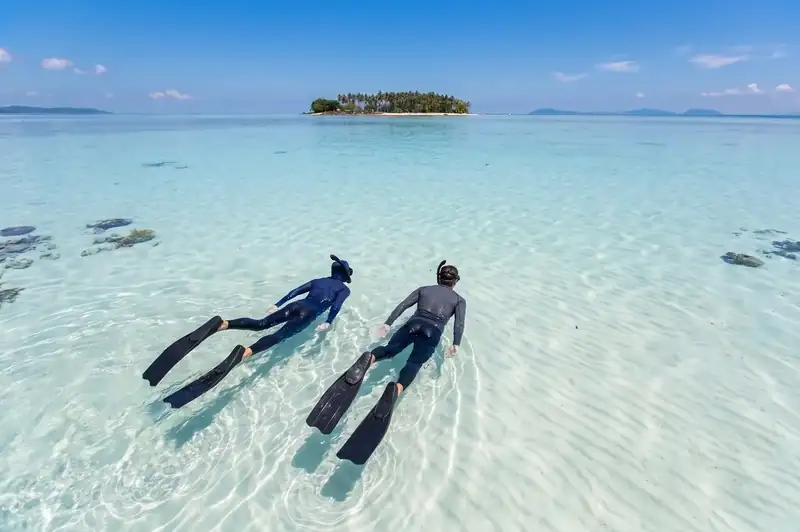 An expert dive buddy guiding scuba divers with Mussah Poteh Resort near Semporna
