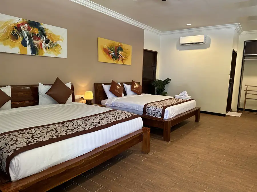A well-appointed bedroom showcasing two large beds with decorative artwork at Mussah Poteh Resort